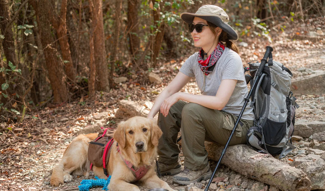 A dog and owner resting on a hiking trail with a food container